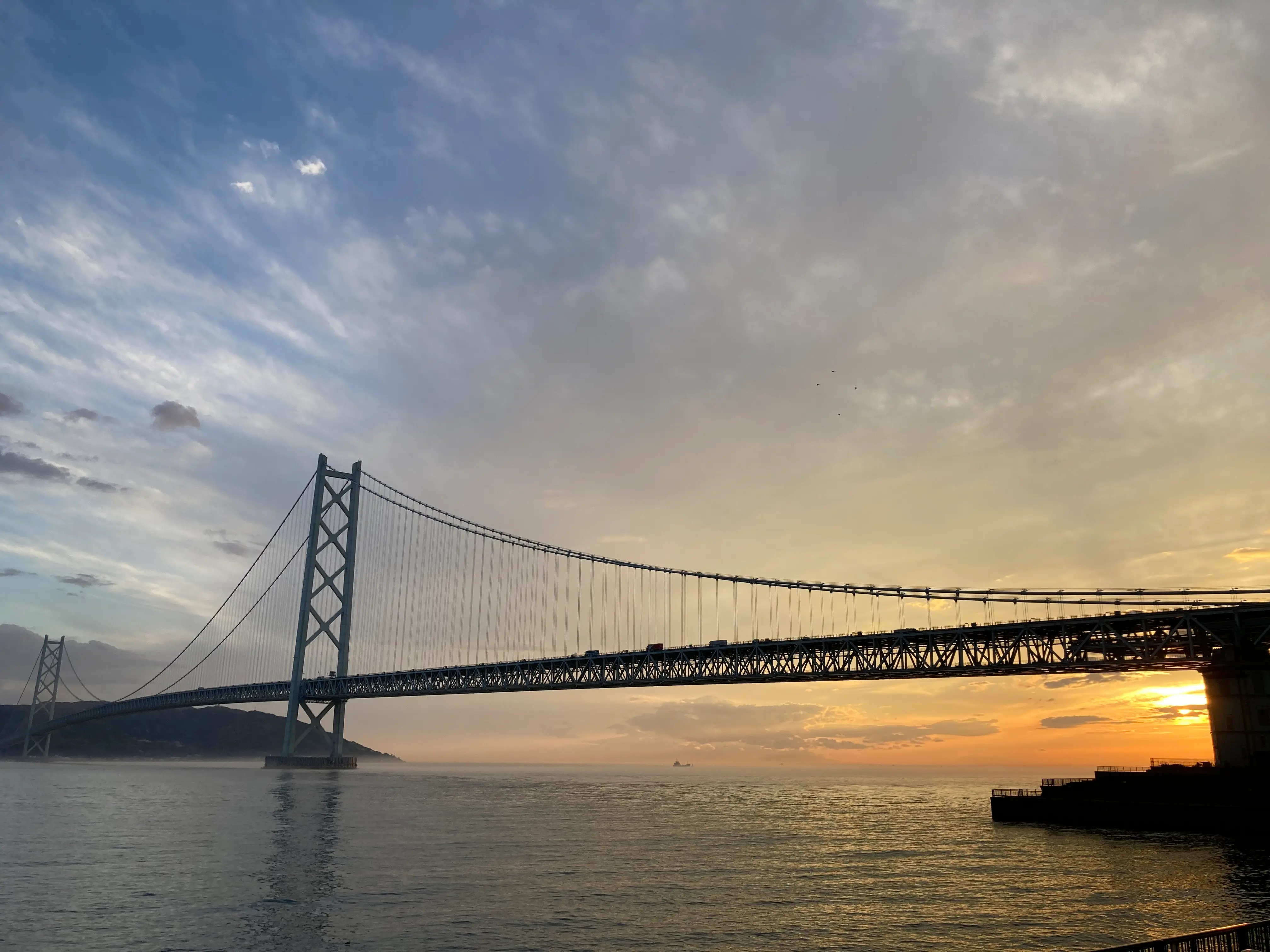 味鉄舞子店の目の前に望む、夕日に美しく染まる海と明石海峡大橋のシルエット